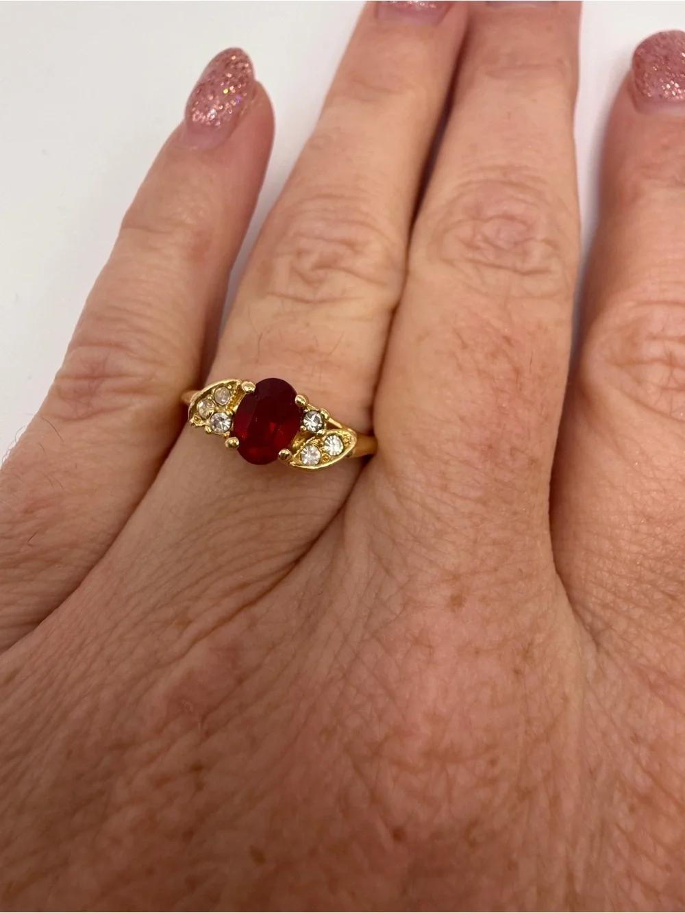 Gold Ring with Oval Red Center Stone and Clear Accent Stones